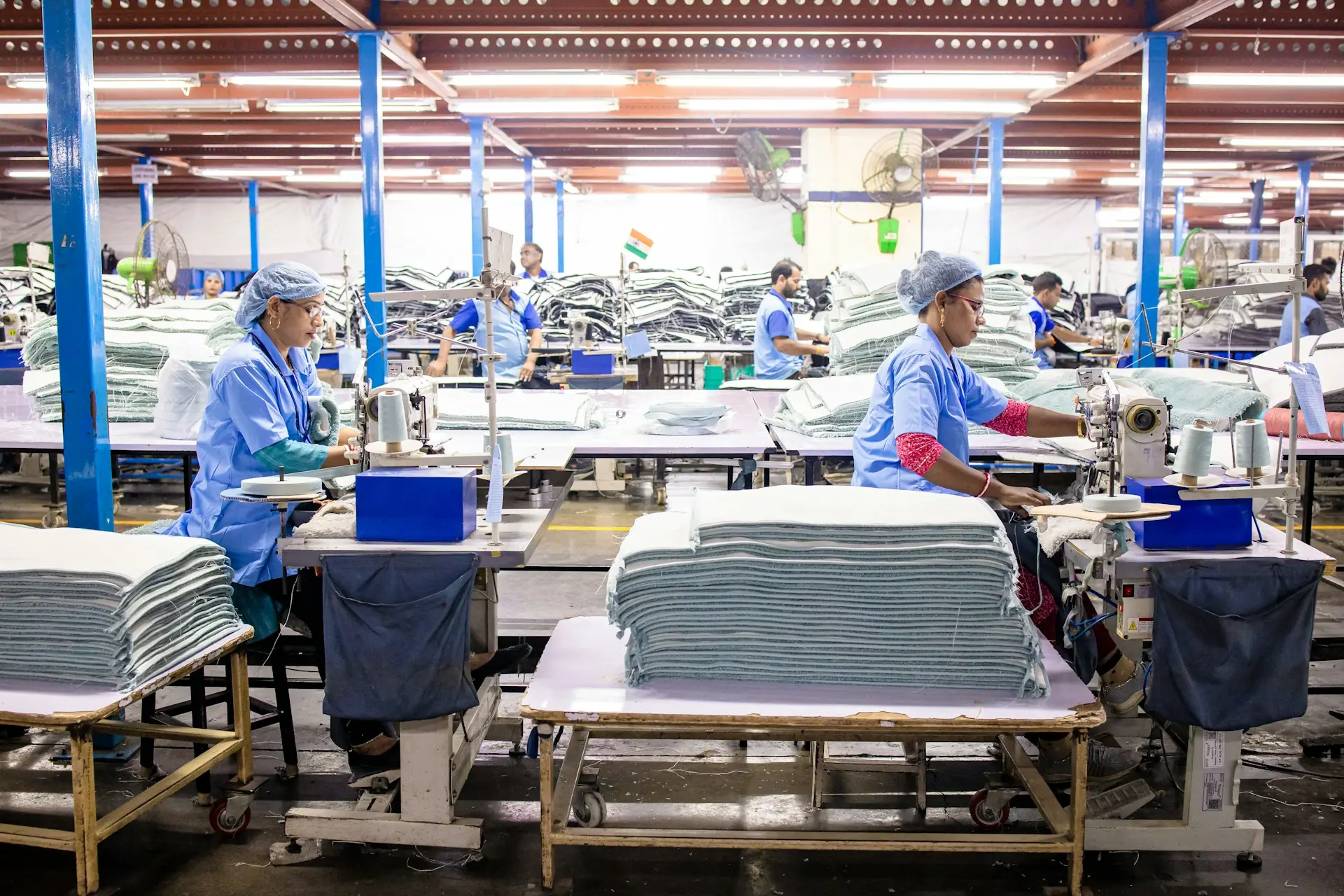 Workers sewing textiles on a large factory floor