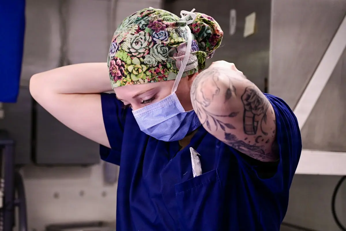 Healthcare professional adjusting a surgical mask and cap